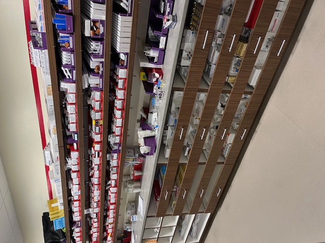 An image a pharmacy fill station with shelves full of prescriptions and pharmaceutical equipment.