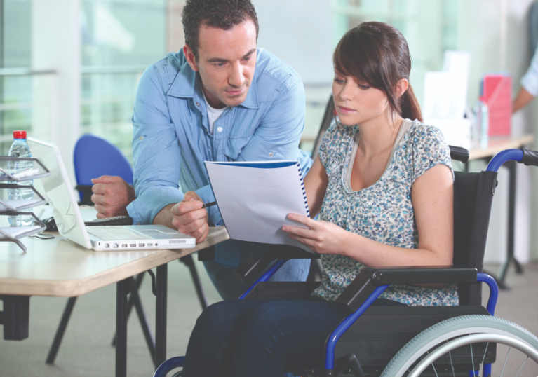 Man sitting next to a woman in a wheelchair reading a document